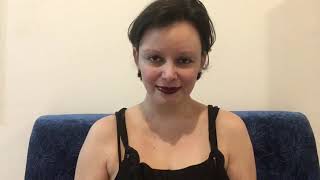 artista em centro em meio a um fundo neutro e uma poltrona