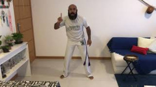 professor de capoeira em meio a uma sala com sofa e estantes
