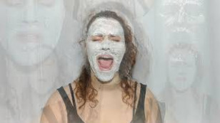 a artista está em centro com uma máscara de creme cobrindo seu rosto enquanto grita. 