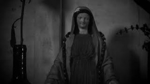 escultura de uma santa em preto e branco com plantas aparecendo nas laterais