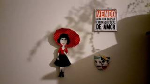 em uma parede aparece colado o desenho de uma pessoa segurando um guarda chuva, uma ilustração de mascaras de teatro e uma placa com os dizeres "vendo [inteligivel] de amor"
